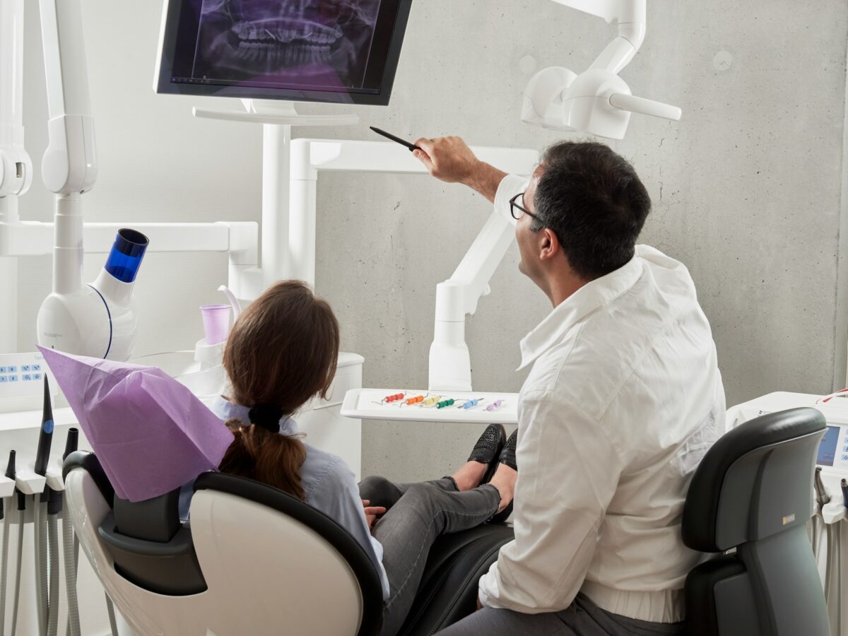 A dentist shows a patient a dental X-Ray