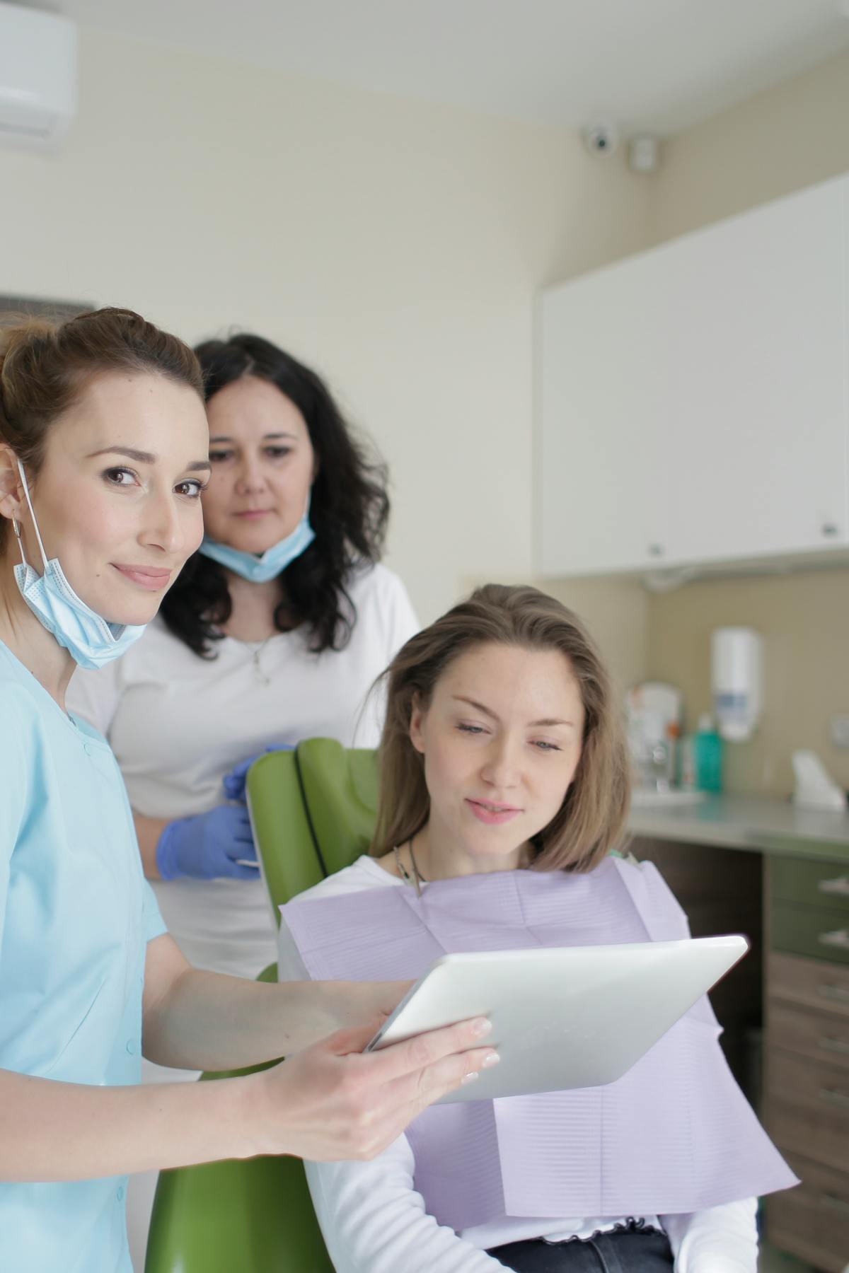 Cheerful stomatologist and assistant showing medical report to patient