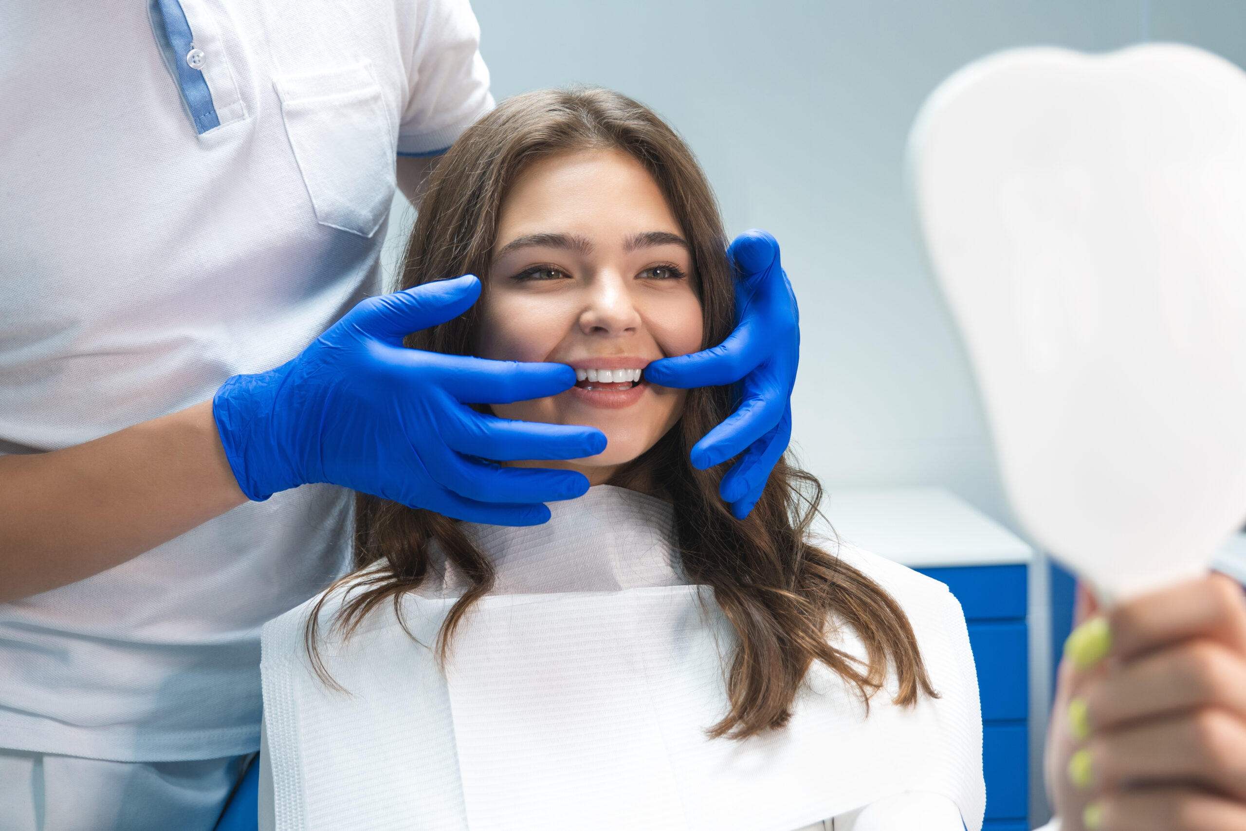 Sealants 3 beautiful young brunette woman having examination at dentist office while dentist showing whitening results to patient.