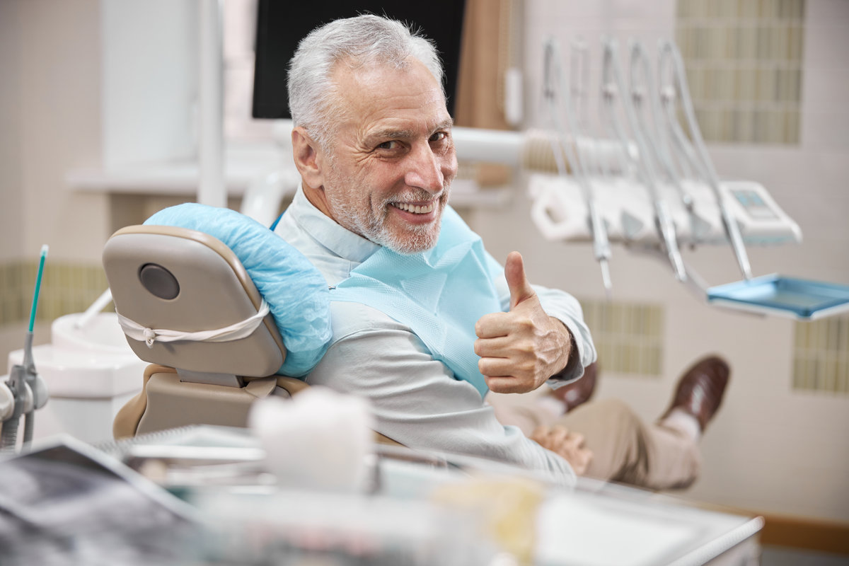 Catasauqua, PA 2 Contented elderly citizen sitting in a dental chair and showing thumbs up while looking at the camera